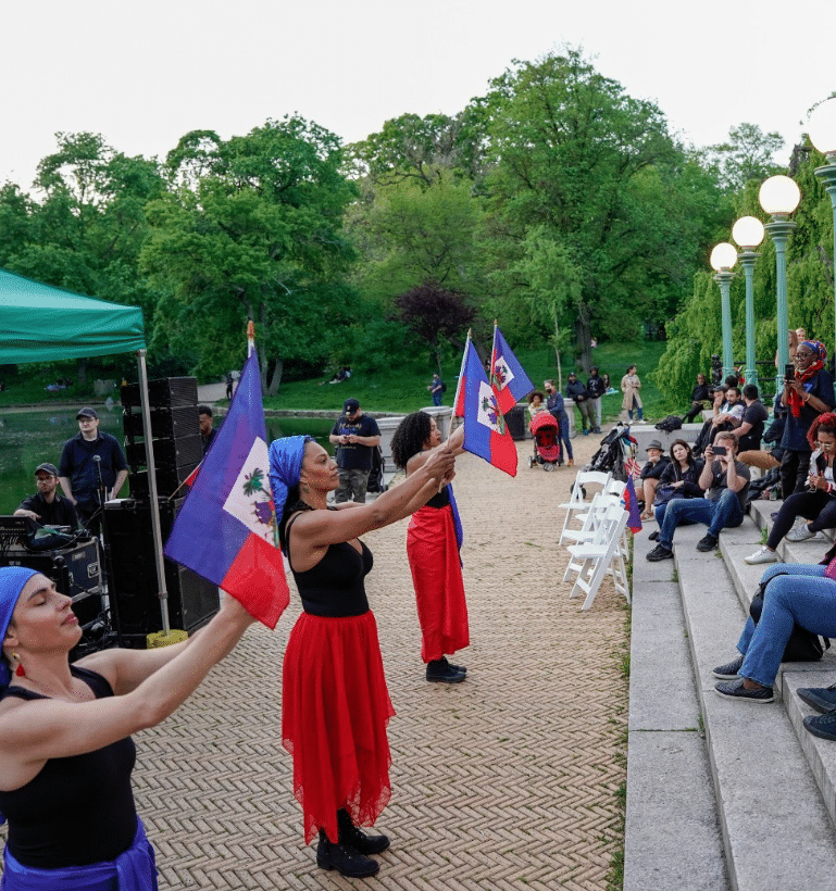 Photo of women holding up flags for Haitian Flag Day