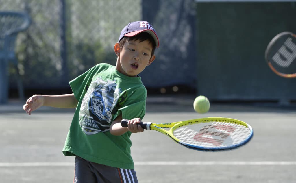 Youth playing Tennis in the summertime.