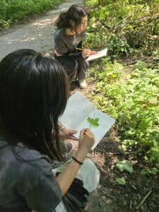 Woodland Youth Crew place leaves in notebook and journal in nature