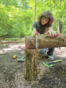 Woodland Youth Crew member saws a log for a rail in Prospect Park