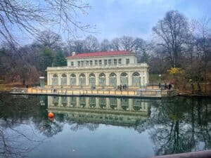 color photo of the Boathouse in wintertime with the clear reflecting water of the lake in front of it
