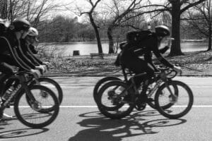 a black and white photo of people cycling in Prospect Park by the lake
